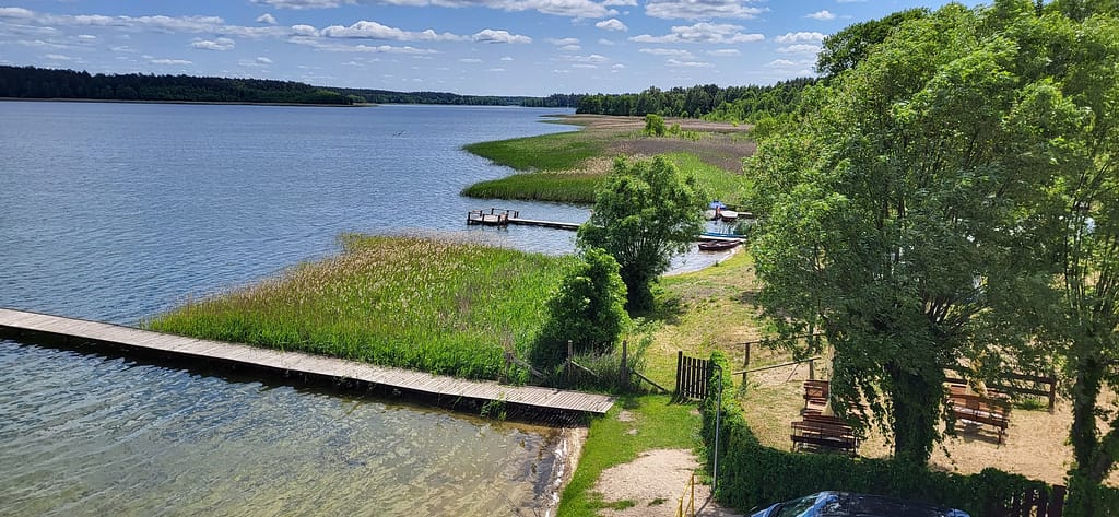 Mazurska Pętla Rowerowa – widok z Wieży Widokowej w Krzyżach na jezioro i przybrzeżne pomosty.