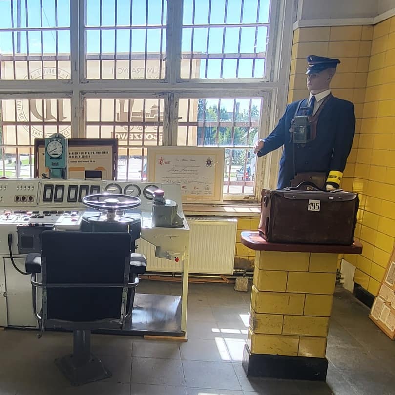 Ekspozycja w muzeum kolejnictwa – stanowisko maszynisty oraz figura konduktora, przywołujące klimat dawnych podróży kolejowych.