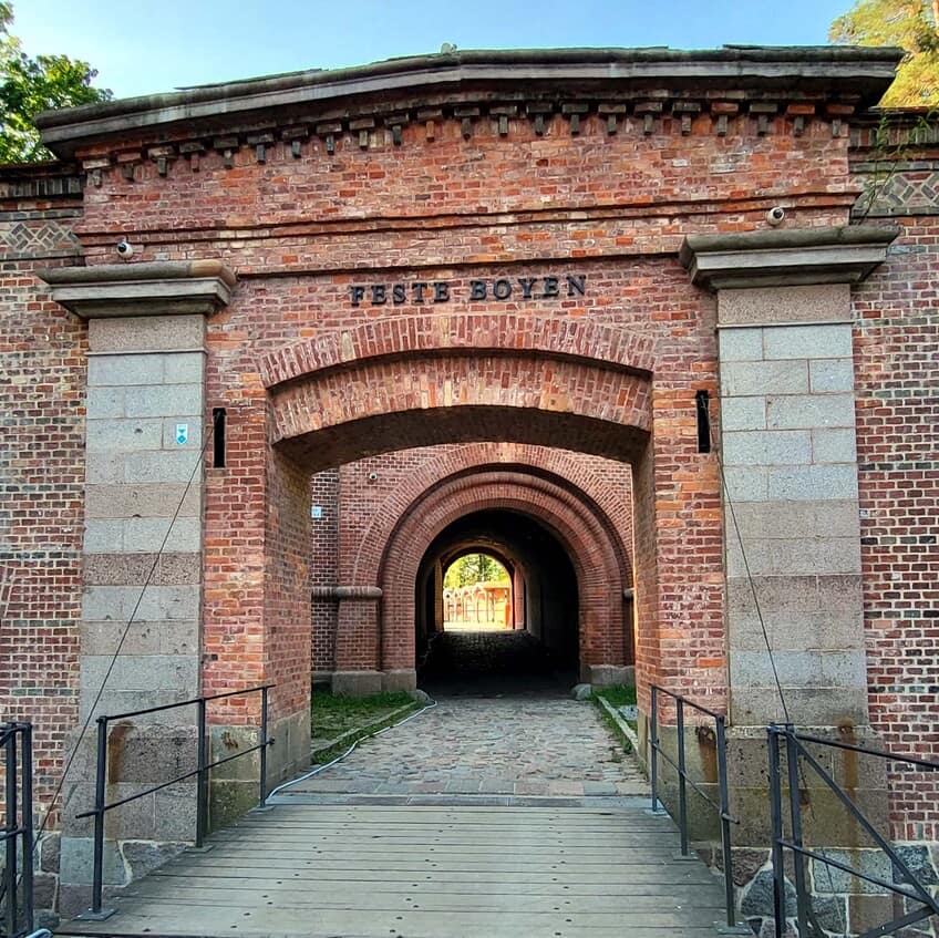 Mazurska Pętla Rowerowa: Twierdza Boyen w Giżycku z ceglanym łukiem bramy i korytarzem.