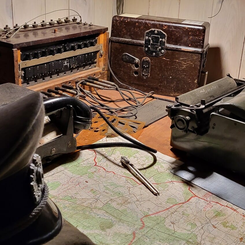 Stanowisko dowódcy z mapą i sprzętem komunikacyjnym – historyczne wnętrze przenoszące w realia dawnych operacji wojskowych.